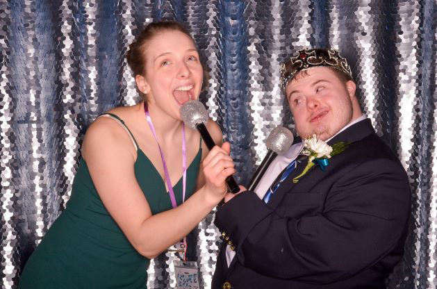 A woman and man posing in a silly way in the photo booth